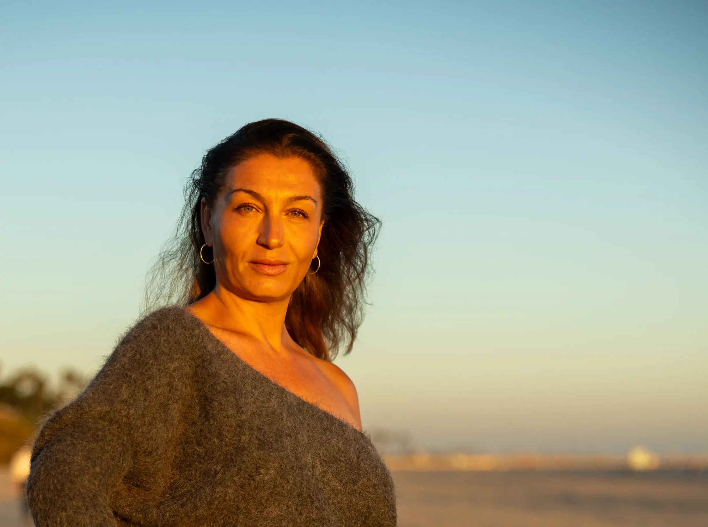 Woman in a one-shoulder sweater gazing confidently at the camera at Bluff Park, Long Beach