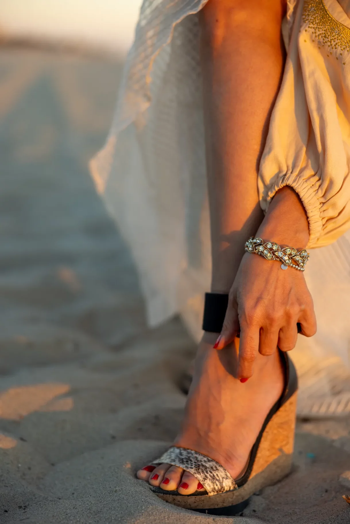 Woman adjusting strap on her sandal at the beach in Long Beach, Los Angeles
