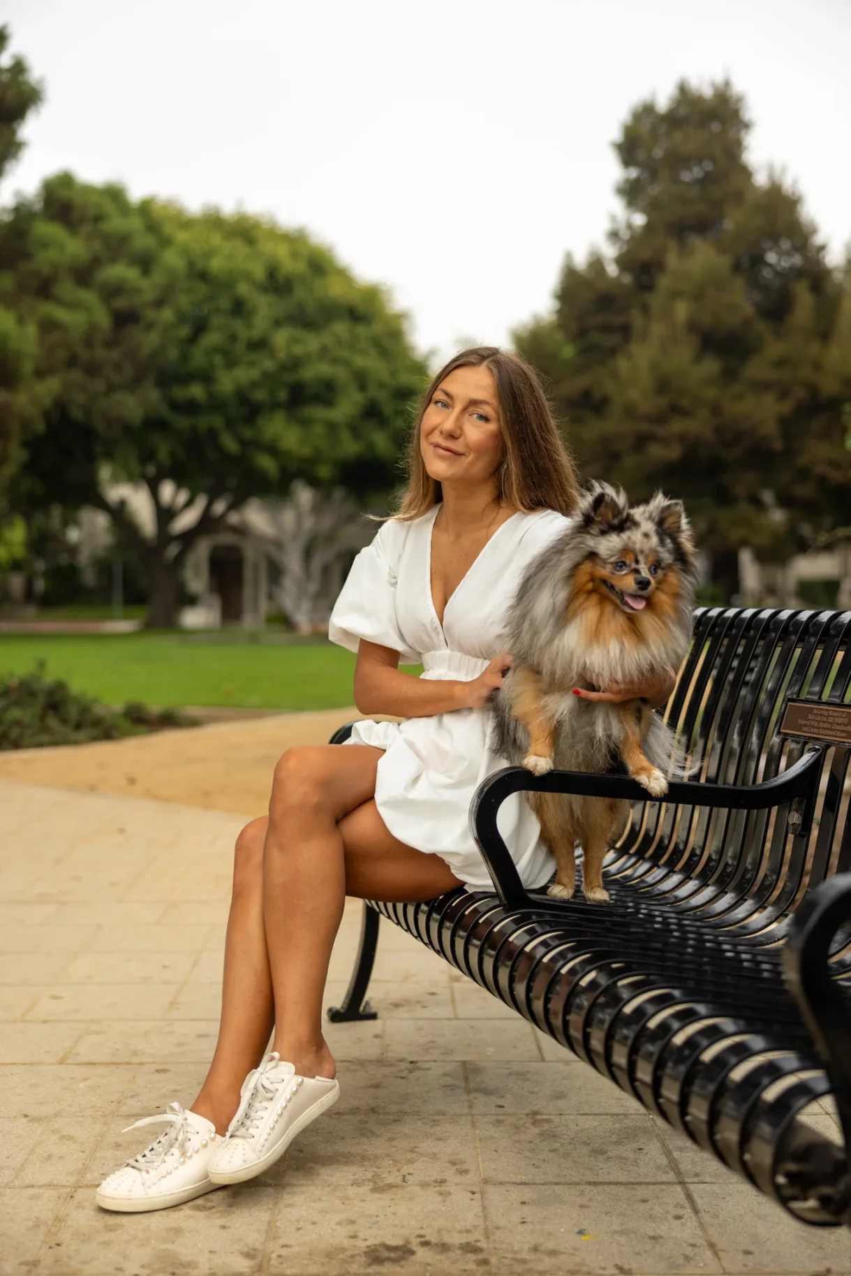 Woman sitting on a bench with her Pomeranian in Beverly Hills park
