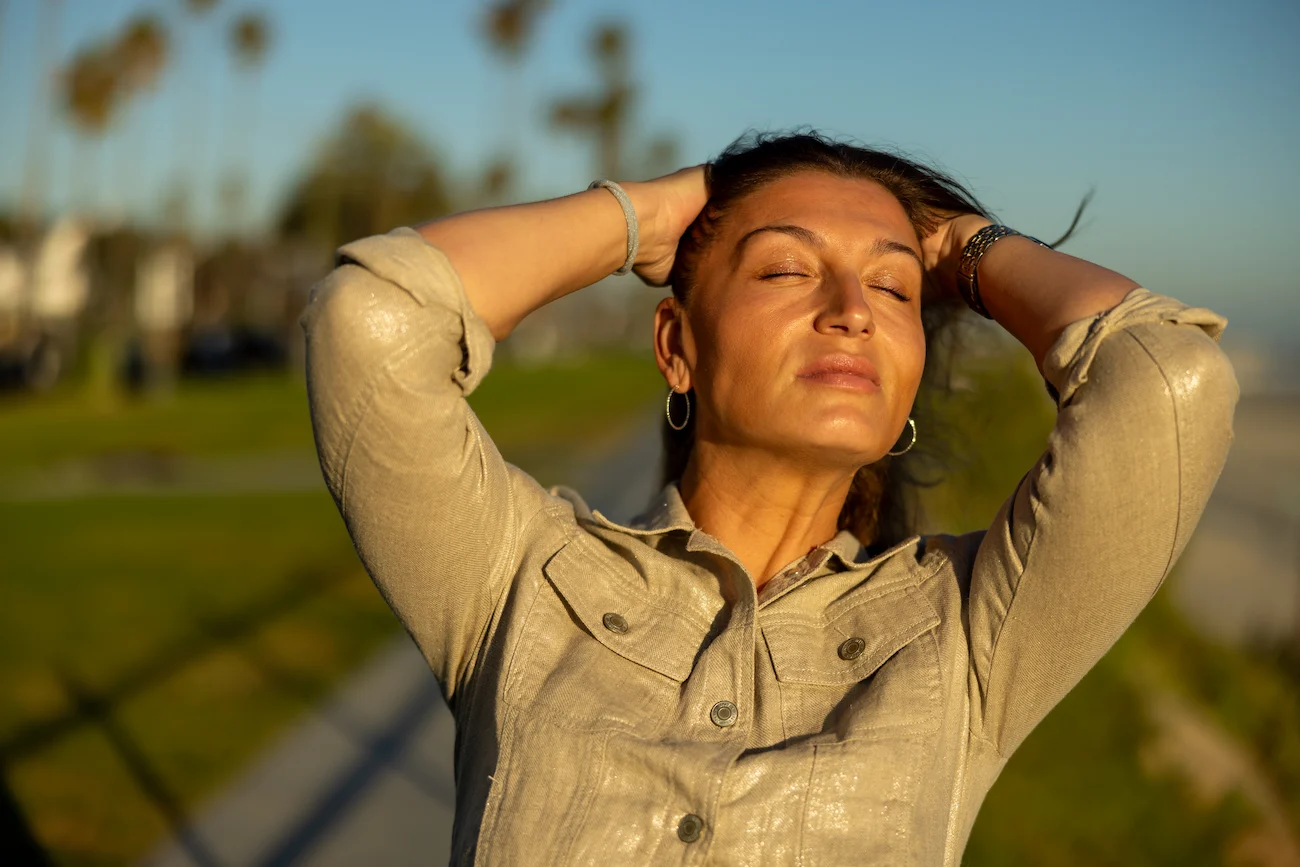 Woman enjoying the sun with hands behind her head in Bluff Park, Long Beach, Los Angeles