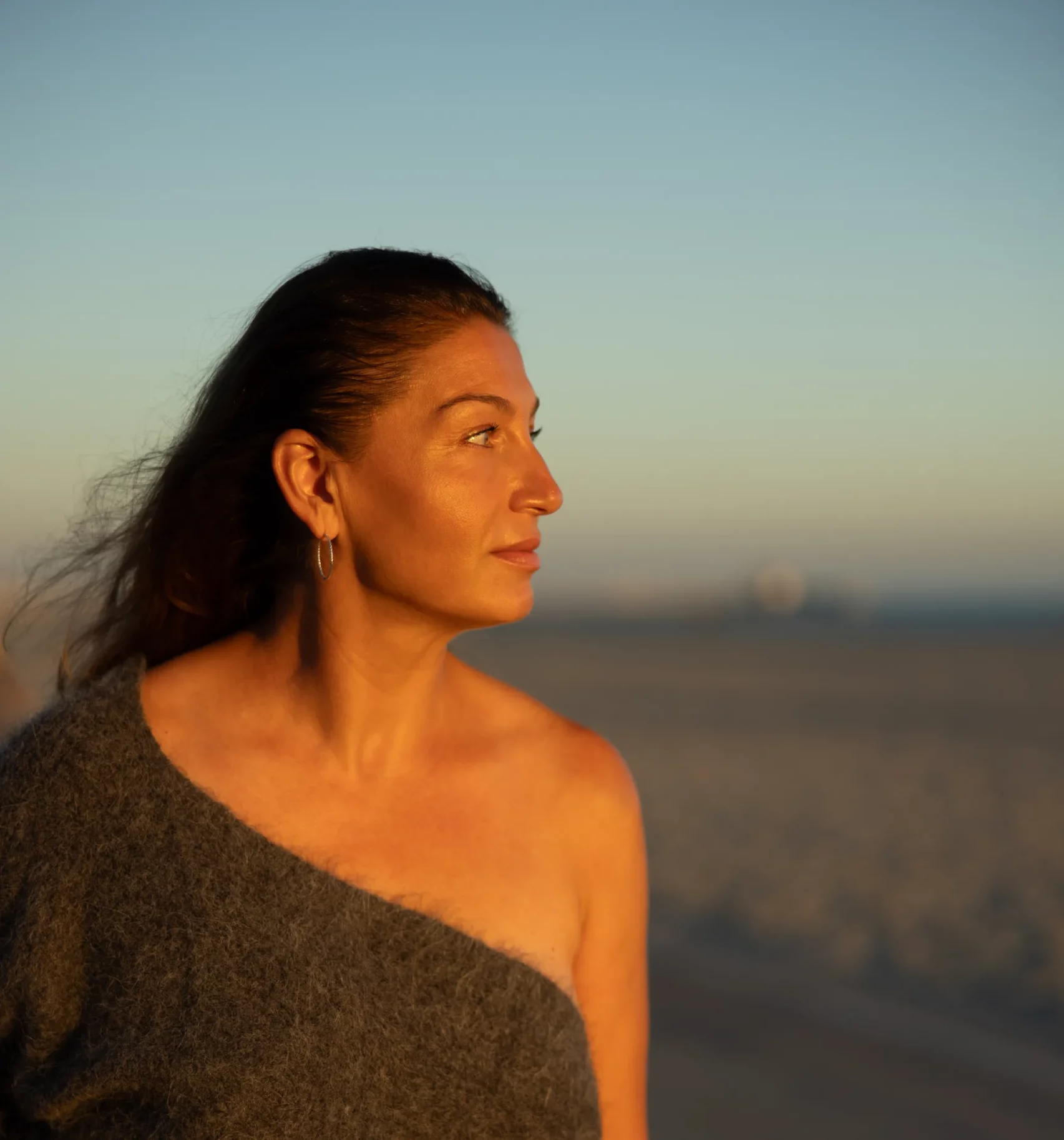 Woman in an off-shoulder sweater looking into the distance at Bluff Park, Long Beach, Los Angeles during sunset