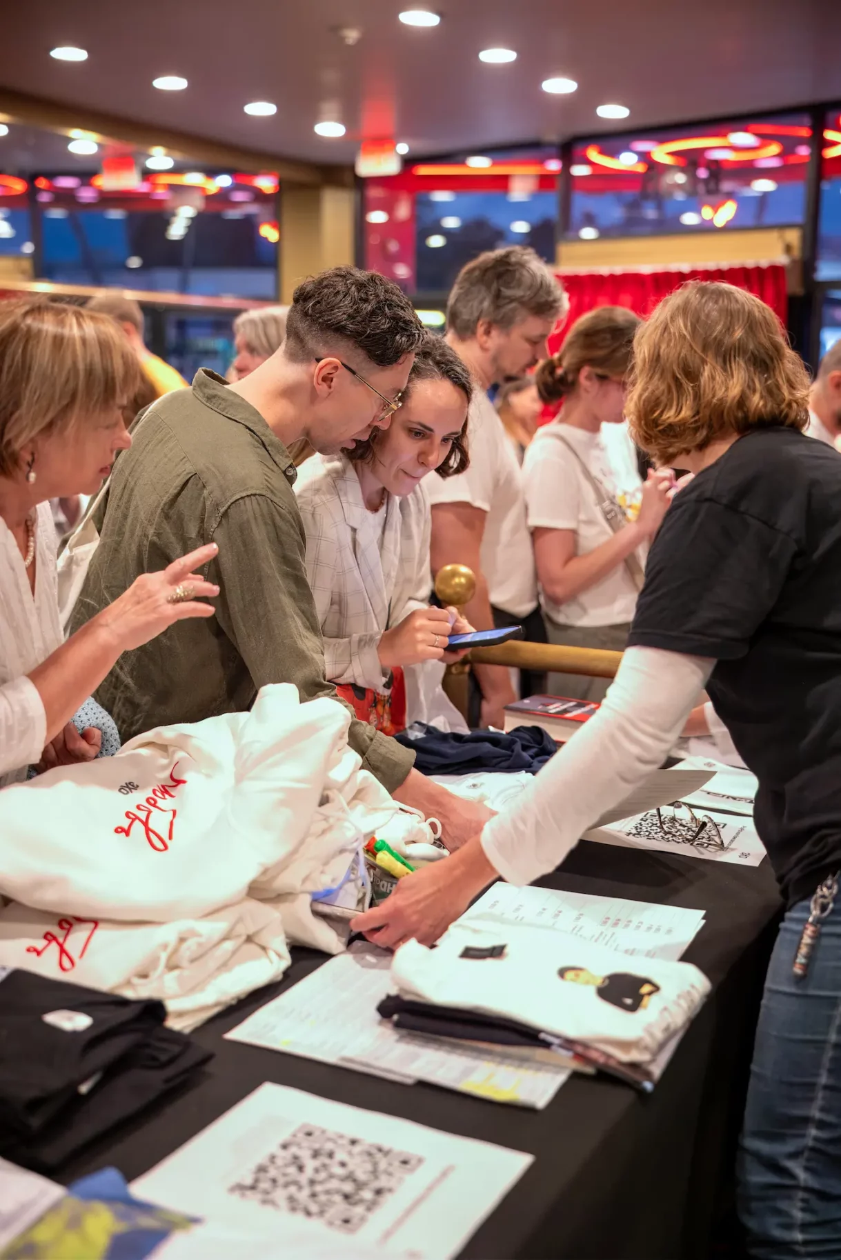 Attendees examining event merchandise at the Fine Arts Theater in Beverly Hills, Los Angeles, with close-up view of a couple discussing items on the table.