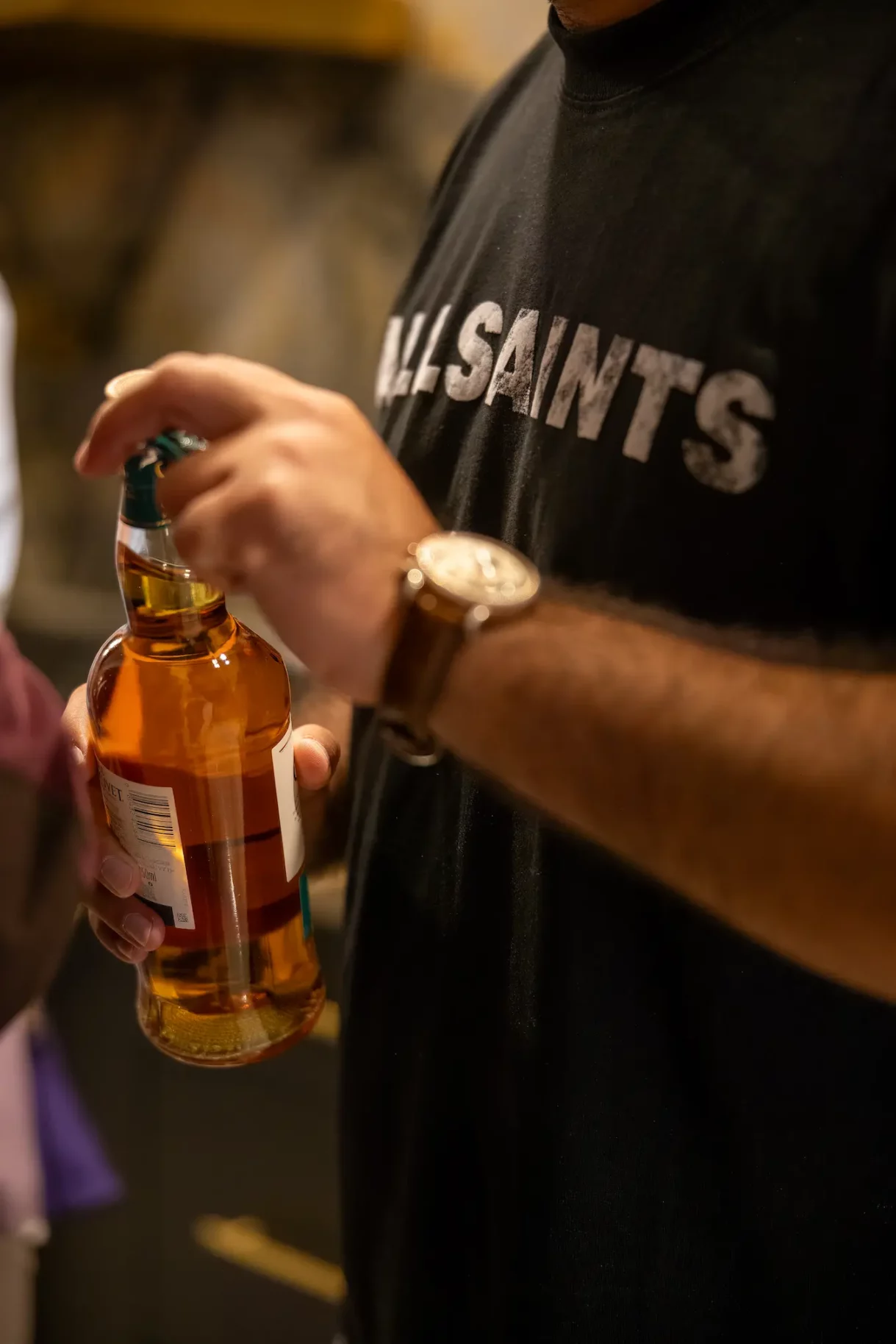 Guest holding a bottle of whiskey, preparing to open it for the celebration.