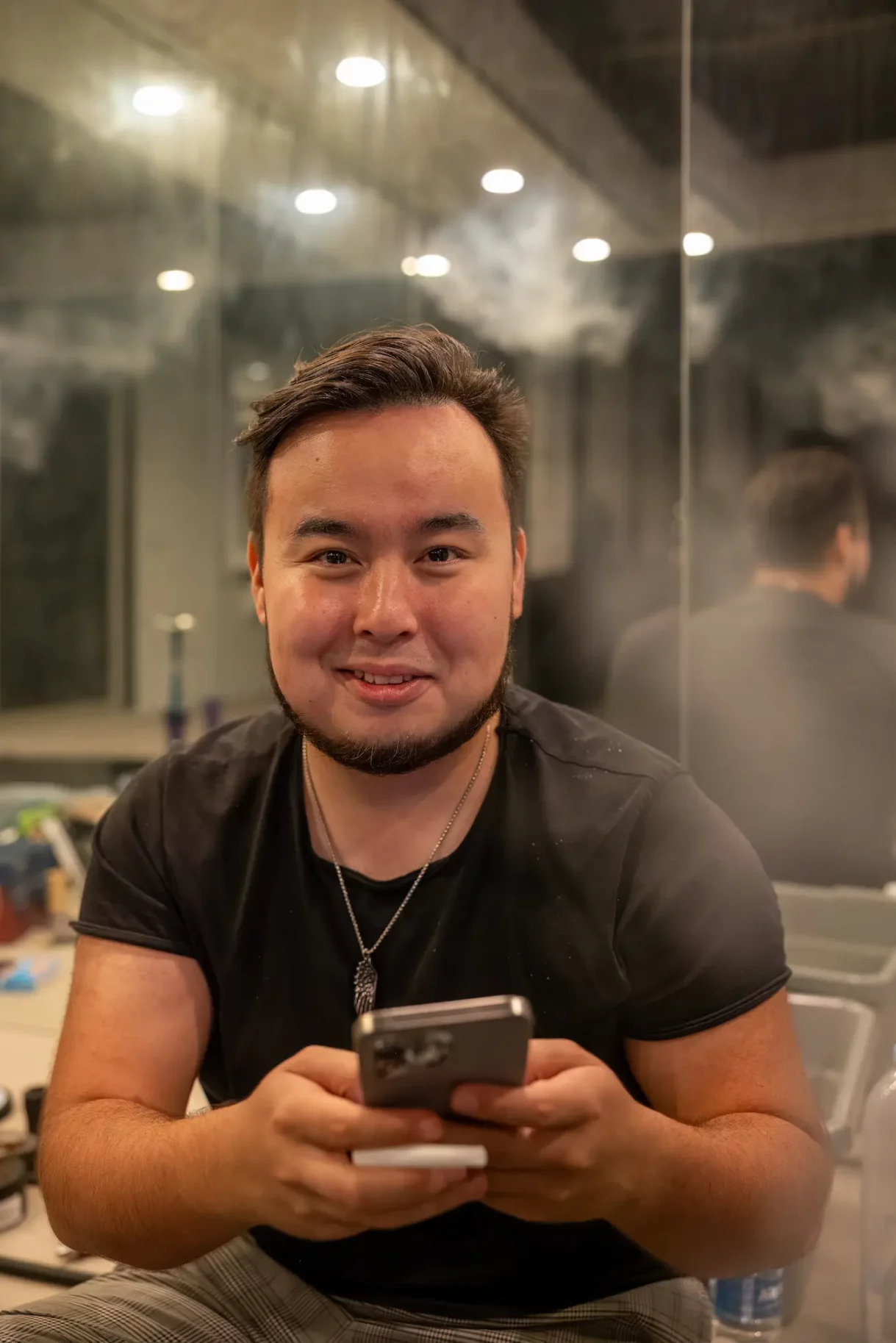 Guest at Beverly Hills party holding his phone with a cheerful expression