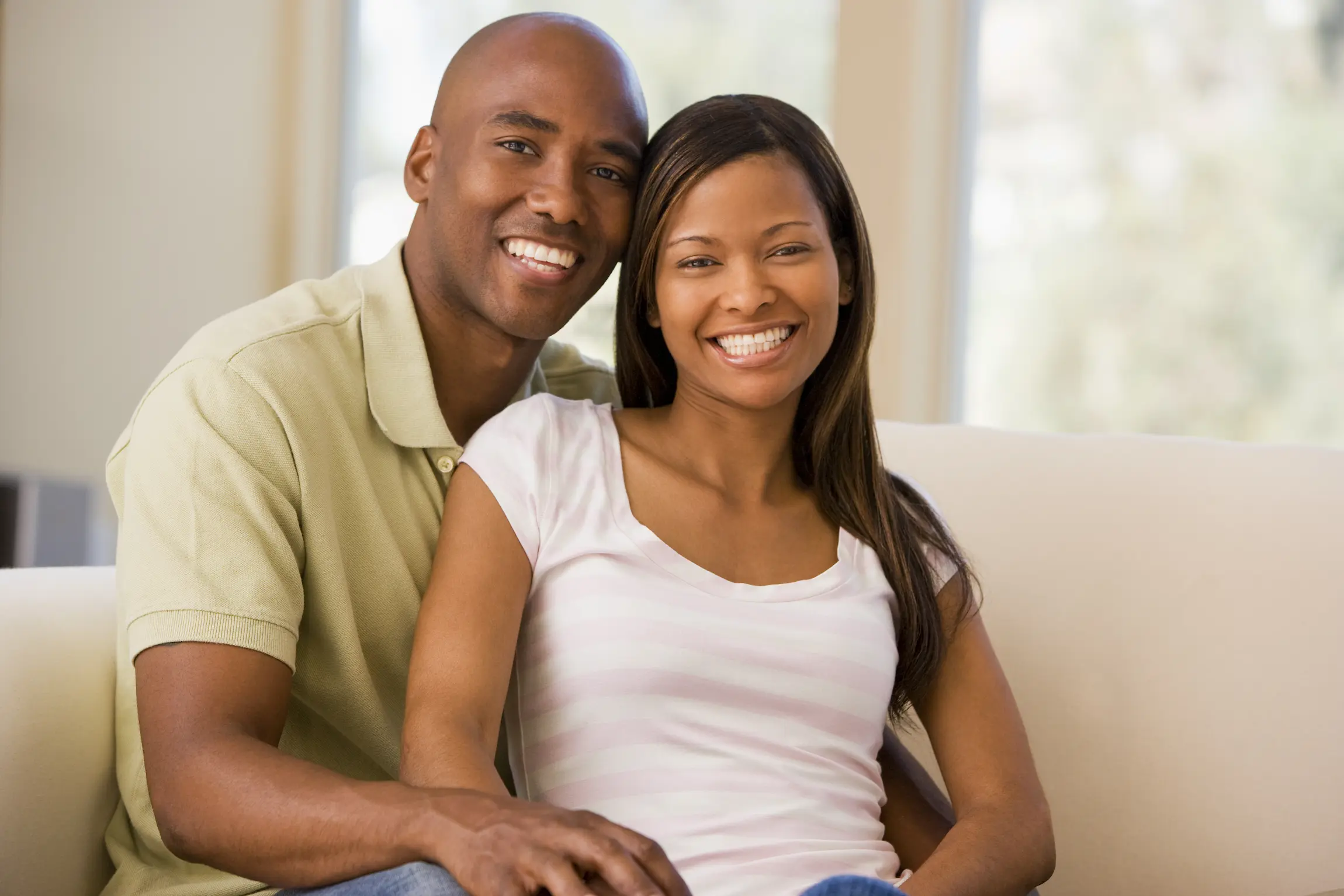Pareja feliz sonriendo durante una acogedora sesión de fotos en casa en Los Ángeles.