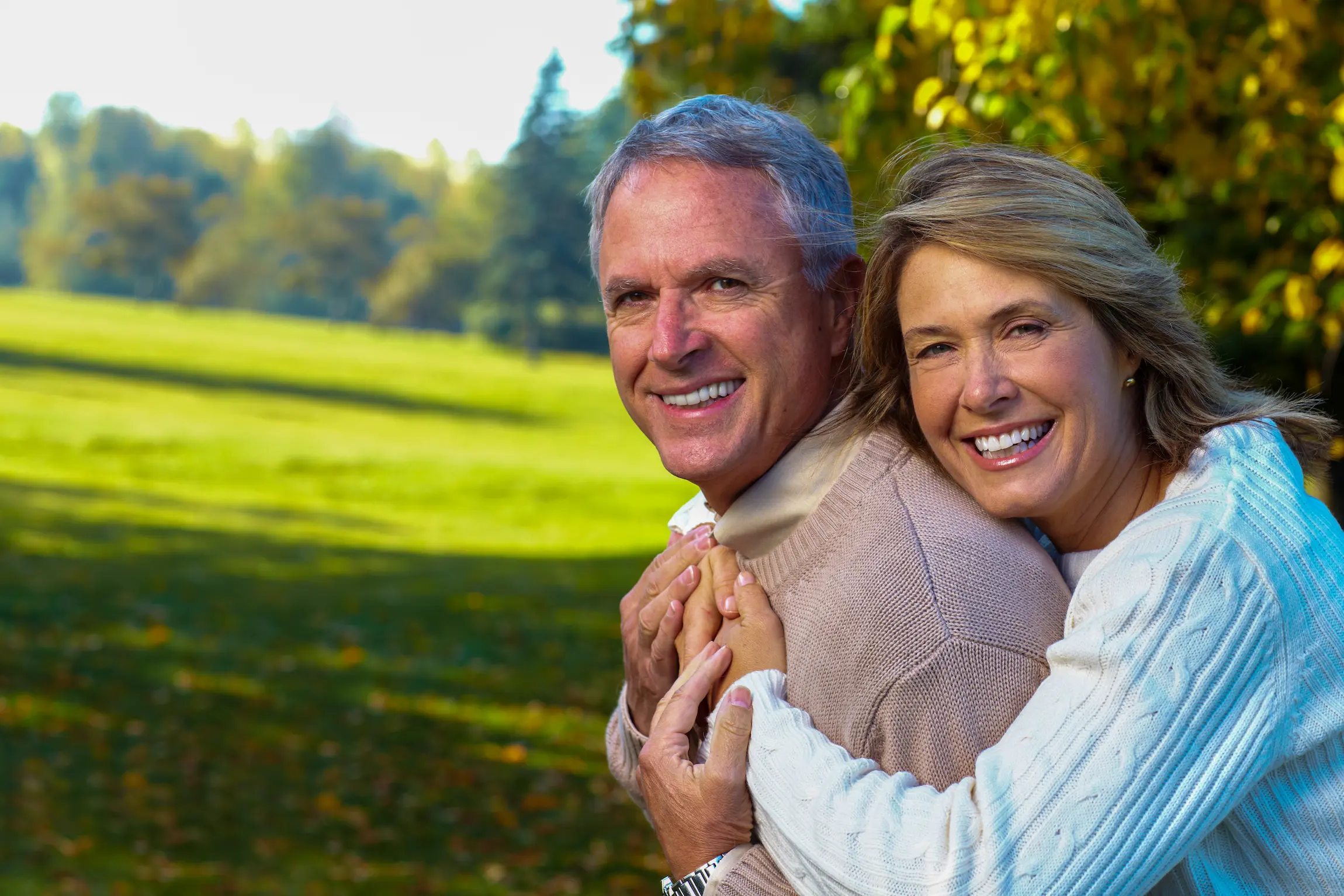 Pareja sonriente disfrutando de una sesión de fotos al aire libre en la hora dorada, en un parque de Los Ángeles.