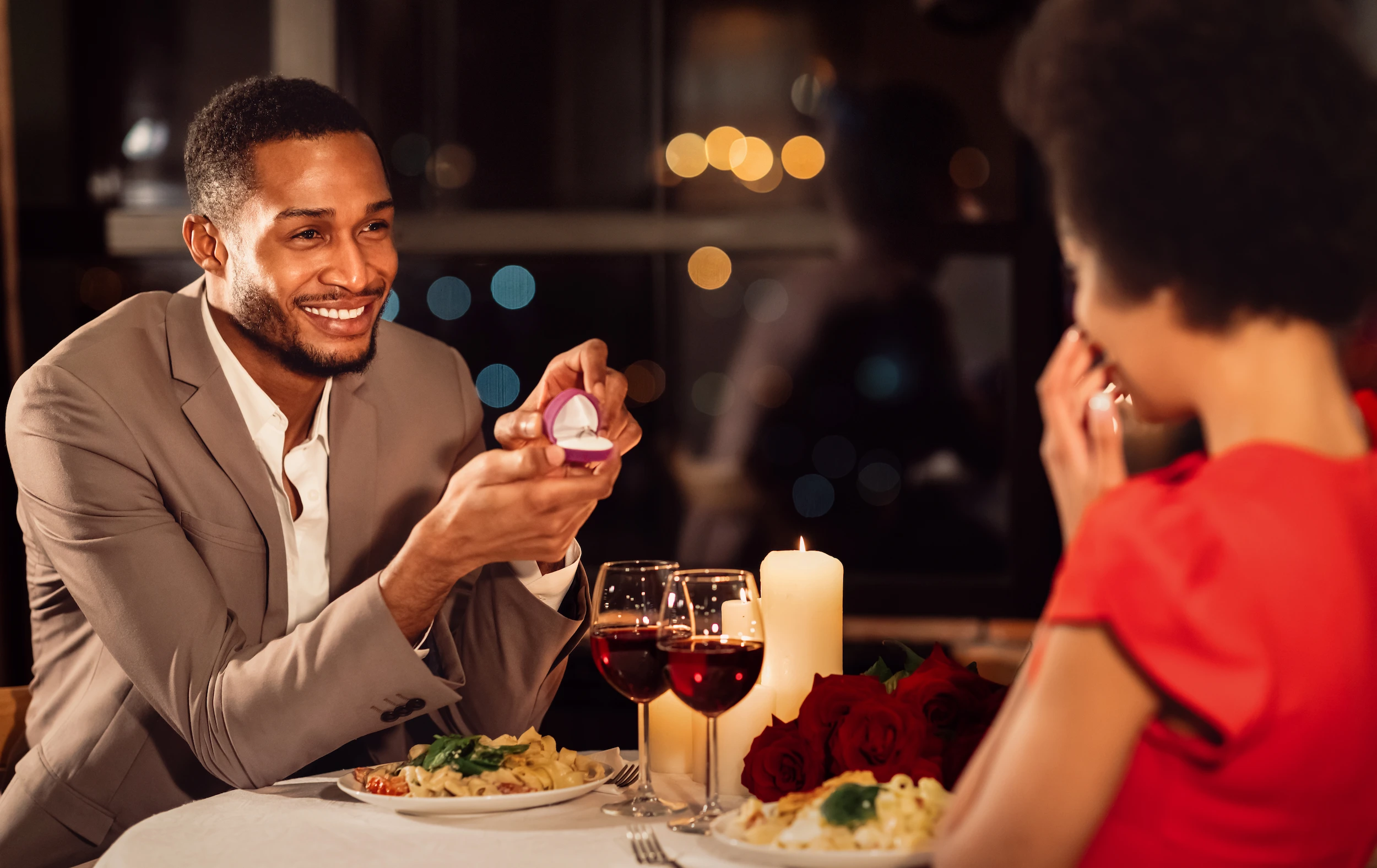 Una emotiva propuesta de matrimonio durante una romántica cena a la luz de las velas: un hombre le ofrece un anillo a su pareja en un restaurante íntimo.