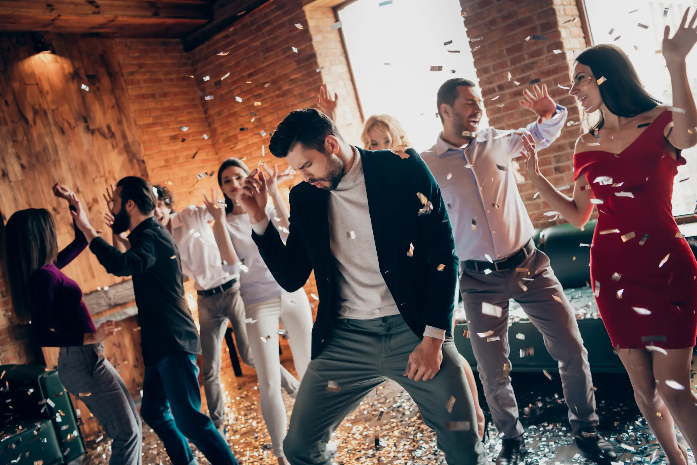 Un grupo de colegas baila con entusiasmo en una fiesta corporativa, entre una lluvia de confeti.